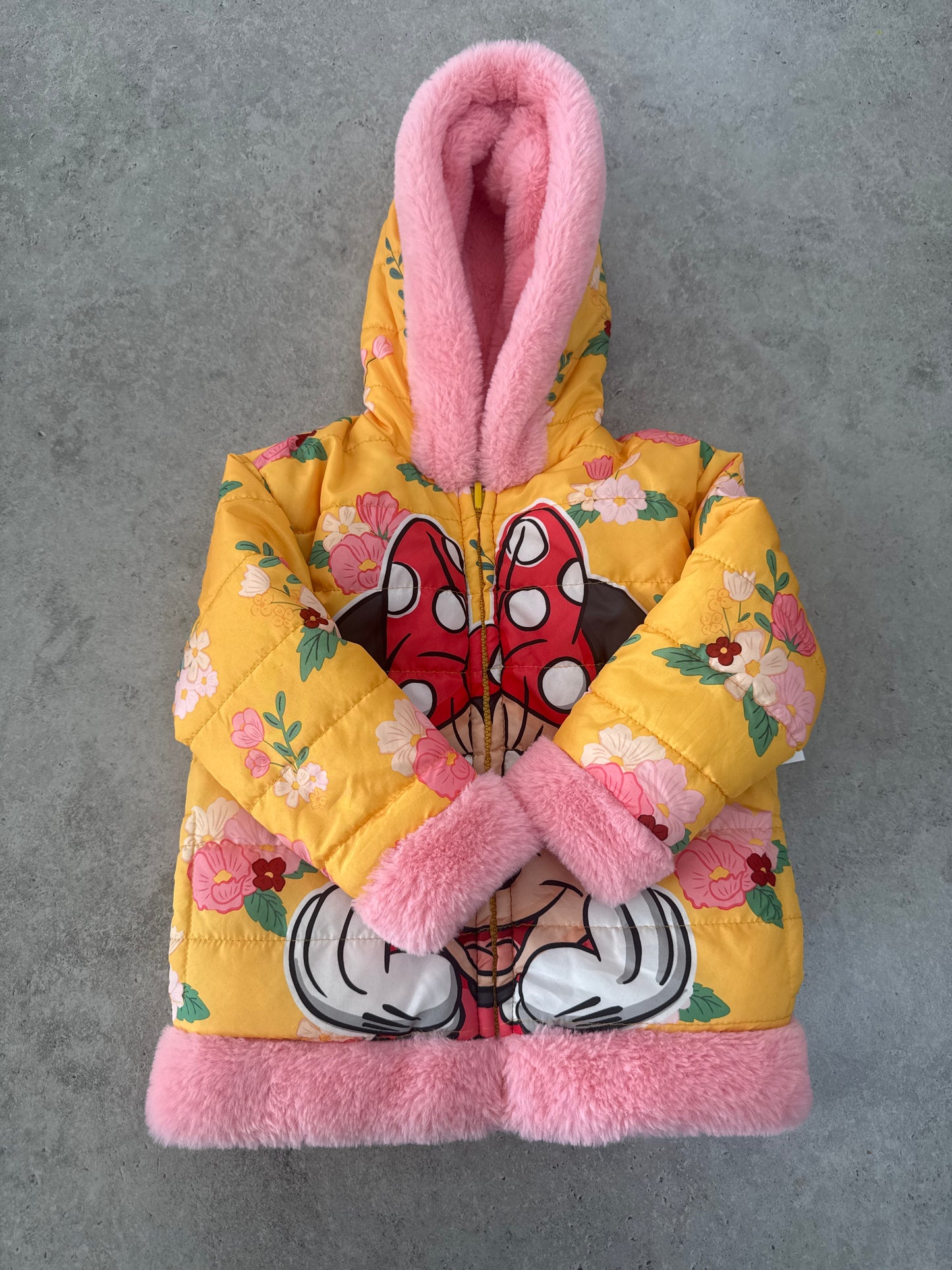 Disney Junior Minnie Mouse reversible puffer jacket with a hood and faux fur trim.